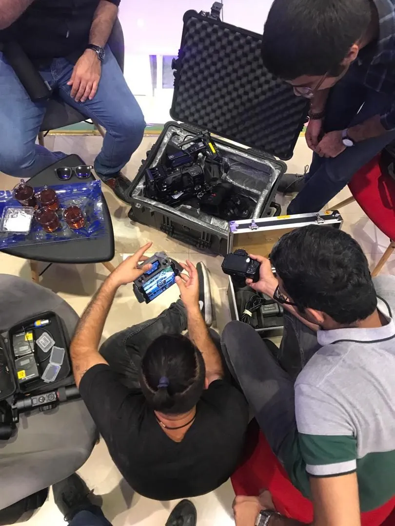Crew members prepare a cinema camera and a stills camera around an open equipment case