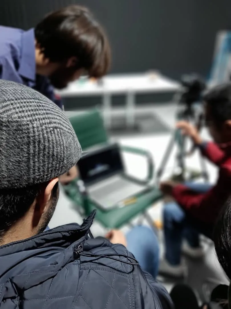 A crew member watches the laptop monitor while the camera operator frames the shot