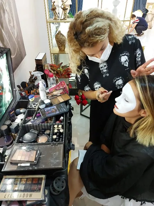 A makeup artist paints a white mask on a model before a shoot