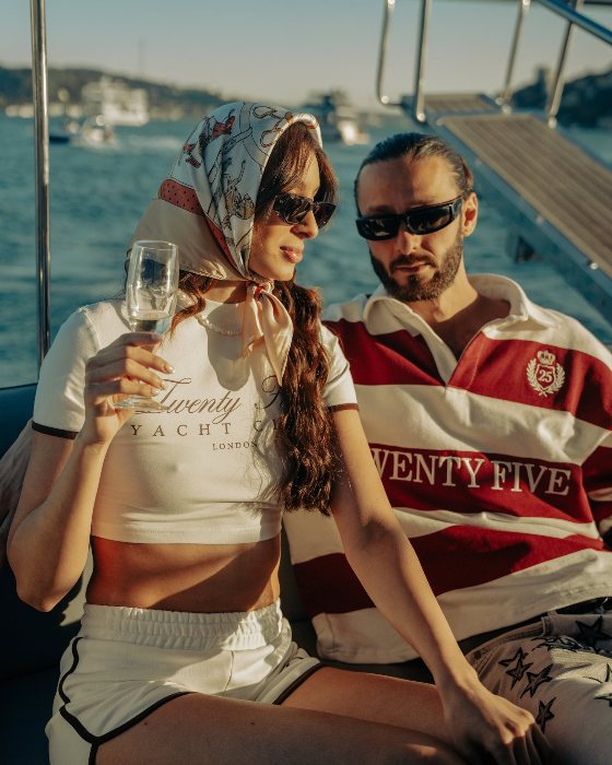 Two models on a boat deck, one in a Twenty Five rugby shirt